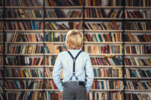 Menino olhando diversos livros em uma biblioteca