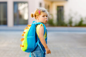 Menina com o rosto triste e mochila escolar